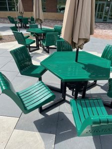 Multiple green metal picnic tables with green metal chairs.